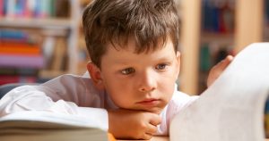 Élève réfléchissant devant un livre.